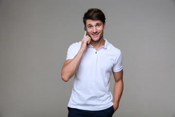 Cheerful handsome young man talking by mobile phone.