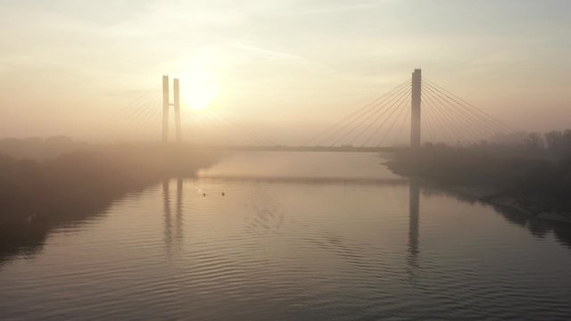 Aerial view of the Siekierkowski Bridge in beautiful fog. Warsaw, Poland. Drone shot at the traffic of vehicle traveling in traffic jam on a bridge over a river.