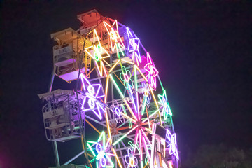 The ferris wheel with decoredt many lights at night.