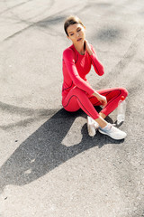 Fitness sport woman in fashion sportswear doing yoga fitness exercise in the city street over gray concrete background. Outdoor sports clothing and shoes, urban style. Sneakers closeup.