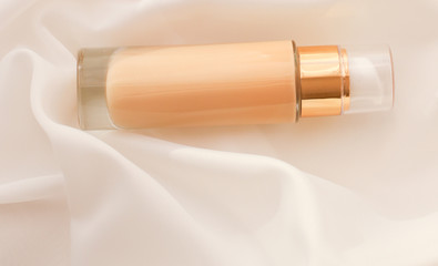 Tonal bb cream bottle make-up fluid foundation base for nude skin color on silk background,...