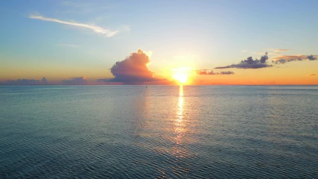 Aerial of an amazing sunset over the ocean, drone flying forward towards the horizon - Bora Bora, French Polynesia