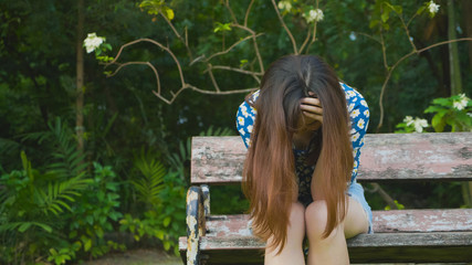 Desperate, crying woman sitting on the bench at the park. hands on face. Feeling of people.