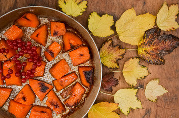  Fried baked on grill pumpkin, a traditional autumn snack.Warm dish as a dessert.On a baking sheet, on a rustic wooden old table with yellow leaves and viburnum.Top view copy space,food for Halloween