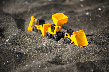 Toy construction machinery in black sand