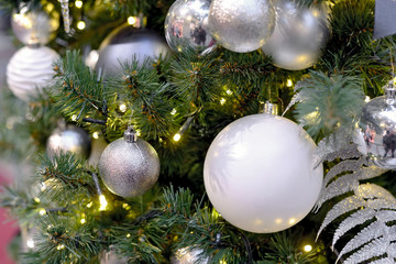 White and silver Christmas balls and garlands on Christmas tree