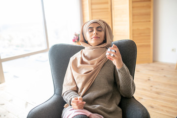 Pretty woman sitting in the chair enjoying the new smell of perfume