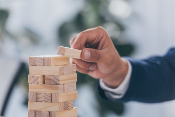 cropped view of businessman putting wooden block on stack