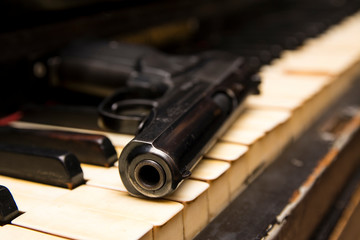Dlack gun on the keys of piano close up