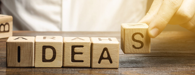 Wooden blocks with the word Ideas and businessman. Generation of innovative business ideas....