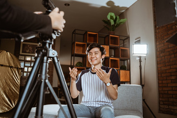 Asian young man blogger recording vlog talking to camera when work at home