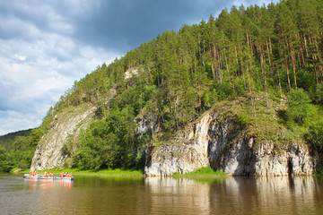 A group of people floating on the river in inflatable catamarans among the beautiful rocks and...