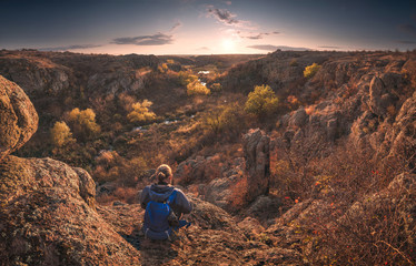 Man sitting on a cliffs edge above the mountain canyon