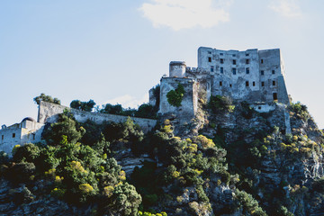View from sea on Aragonese castle surrounded by sea, town a port with boats on Ischia island in...