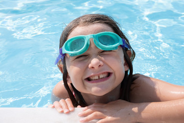 female child by the pool side pulling faces to the camera