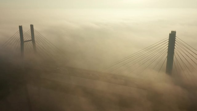 Aerial view of the landmark of the bridge in the fog in Warsaw. Drone flies above the clouds of fog and the Vistula river at sunrise. Spectacular Sunrise with low fog. bridge Siekierkowski, Warsaw.