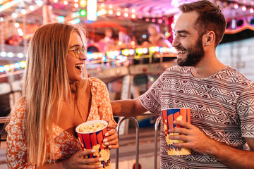 Loving couple walking in amusement park eat popcorn. © Drobot Dean