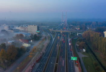 Aerial view of the drone shows the impressive elevation of the highway and the convergence of roads, bridges, viaducts on a foggy morning in Warsaw, Poland.