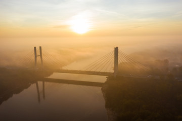 Aerial view of the Siekierkowski Bridge in beautiful fog. Warsaw, Poland. Drone shot at the traffic of vehicle traveling in traffic jam on a bridge over a river.