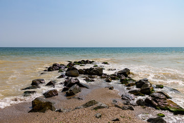 Sea seaside with stones, Waves clean blue water and blue sky on the background.