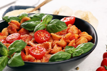 Pasta orecchiette. Plate of delicious orecchiette with tomato sauce garnished with parmesan cheese and basil on rustic background