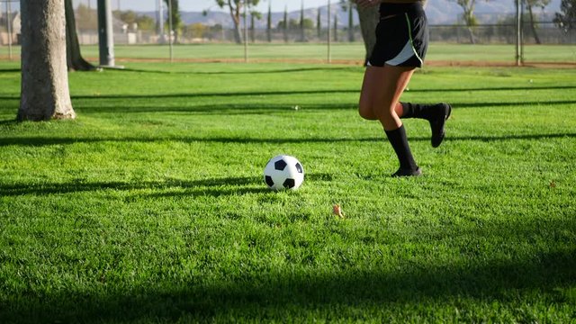 A female womens soccer player running and dribbling a football up the field during a team sports practice SLOW MOTION.