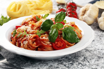 tagliatelle pasta with tomato sauce parmesan basil on rustic background