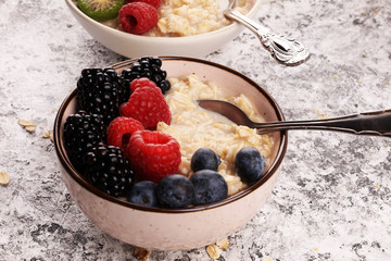 Bowl of oatmeal porridge with banana, raspberries coconut and caramel sauce on rustic table, hot and healthy food for Breakfast