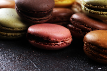 Obraz na płótnie Canvas Sweet and colourful french macaroons or macaron on dark black background, Dessert.