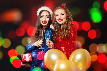 Happy Christmas women friends laughing. Winter fashion girls on abstract bokeh glitter sparkle party background