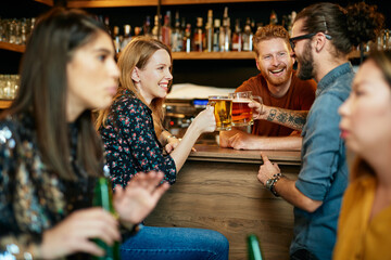 Friends standing in bar and toasting with beer.