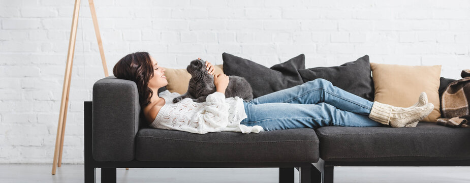 attractive woman lying on sofa with scottish fold cat in cozy living room
