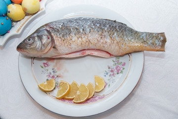 A bass fish with eye's doll inside a flower plate hidden on white background. Minimal quirky color still life photography . inside the fish plate .