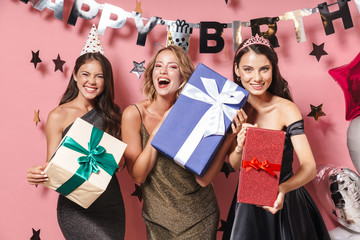 Image of joyful party girls in fancy dresses holding birthday gift boxes