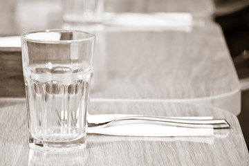glass on top of wooden table with blurry restaurant . Empty glass on the wooden table in cafe. close up .