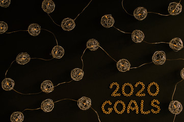 Obraz na płótnie Canvas New Year goals 2020. Black background decorated with Christmas decorations, spherical metallic lights connected with each other.