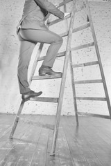 Mature businessman climbing wooden ladder in office