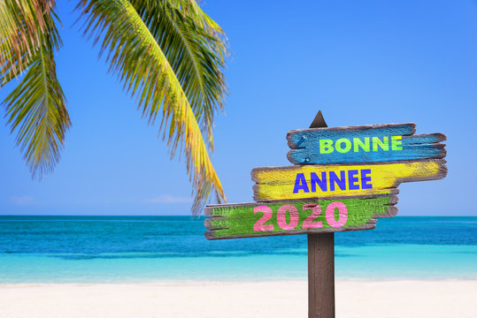 Bonne anneée 2020, écrit en français sur des panneaux de direction en bois sur une plage tropicale