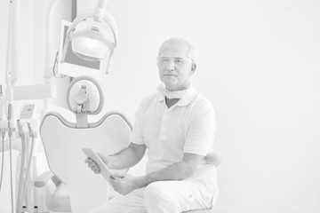 Confident doctor reading medical report on digital tablet at dental clinic