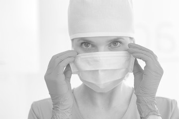 Closeup portrait of female doctor wearing surgical mask and cap at clinic