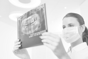 Doctor wearing face mask while examining x-ray at ciinic