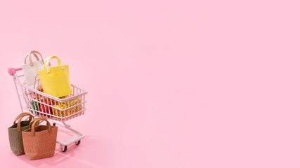 Annual sale shopping season concept - mini pink shop cart trolley full of paper bag gift isolated...