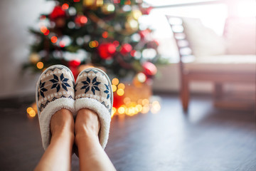 Legs in slippers on Christmas tree background