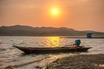A boat on the lake under sun at sunset with panoramic background
