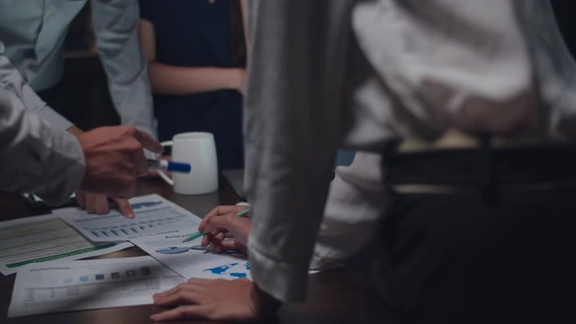 Millennial Asia businessmen and businesswomen meeting brainstorming ideas about new paperwork project colleagues working together planning success strategy enjoy teamwork in small modern night office.