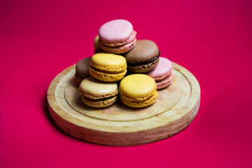 Colored macarons isolated on wooden dish, typical French dish