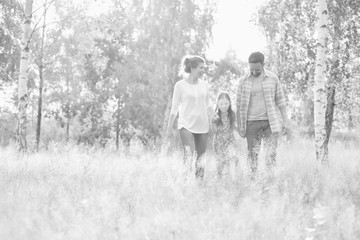 Young Caucasian family walking across woods all holding hands, concept natural lifestyle organic family