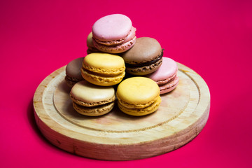 Colored macarons isolated on wooden dish, typical French dish