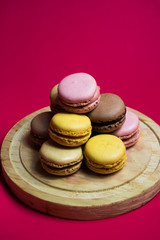 Colored macarons isolated on wooden dish, typical French dish