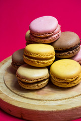 Colored macarons isolated on wooden dish, typical French dish